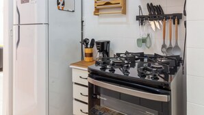 A compact kitchen with a refrigerator, microwave, stove, oven, and a wooden utensil holder. - 14 Minutos Da Praia De Copacabana | Fo801 (Rio de Janeiro)