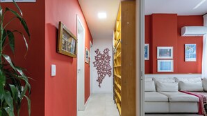 Un soggiorno moderno con una parete di accento rossa, un divano bianco e una libreria in legno.