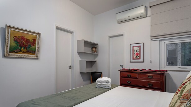 Una camera da letto con un letto, una cassettiera, una scaffalatura e una finestra.