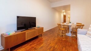 A modern living room with a flat-screen TV on a wooden console, a dining table with chairs, and a sofa. - 5 Minutos Da Praia Do Leme | Gs1102 (Rio de Janeiro)