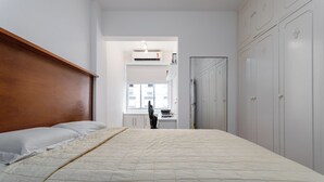 A bedroom with a wooden headboard, a bed with a beige quilt, a desk with a laptop, and a wardrobe. - 3 Minutos Da Praia Do Leme | Gs501 (Rio de Janeiro)