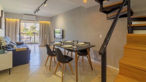 Ein modernes Wohnzimmer mit Essbereich, einer Treppe und Blick ins Freie.