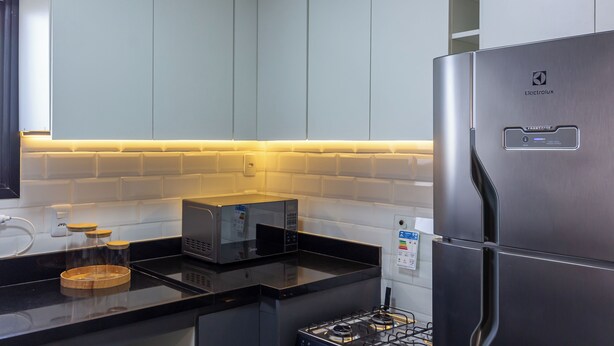 Eine moderne Küche mit einem Edelstahl-Kühlschrank, einer Mikrowelle und einem Gasherd.