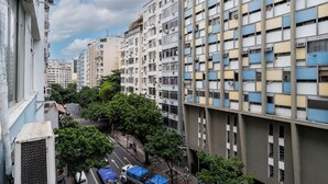 Un edificio alto con numerosi piani, condizionatori d'aria e una strada alberata con veicoli parcheggiati.