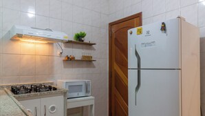 A compact kitchen with white tiled walls, a gas stove, a microwave, and a refrigerator. - Refúgio Em Copacabana Perto Da Praia | I801 (Rio de Janeiro)