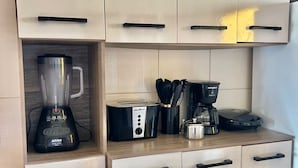 A kitchen with white cabinets, a blender, a toaster, and a coffee maker. - Refugio Brisa Do Campo | Ig - Solar Do Campo (Iguaba Grande)