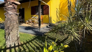 A yellow building with a patio area, surrounded by palm trees and a grassy lawn. - Refugio Brisa Do Campo | Ig - Solar Do Campo (Iguaba Grande)