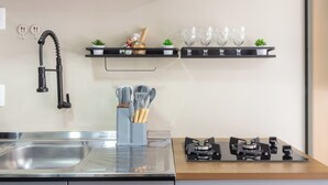Une cuisine moderne avec des meubles gris, un robinet noir, une cuisinière et une hotte noire.