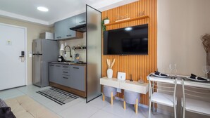A modern kitchen with a built-in oven, a refrigerator, and a dining area with a table and chairs. - Conforto Em Ipanema A 6Min Da Praia | J302 (Rio de Janeiro)