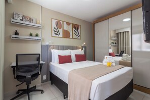 A hotel room with a bed, a desk with a chair, a shelf with decorative items, and a mirror. - Conforto Em Ipanema A 6Min Da Praia | J302 (Rio de Janeiro)