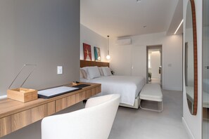 A modern hotel room with a wooden desk, a bed, a bench, and a small seating area. - 5 Minutos Da Praia De Ipanema | J303 (Rio de Janeiro)