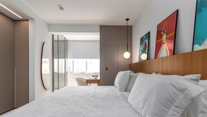 A modern hotel room with a large bed, a desk, and a view of the city. - 5 Minutos Da Praia De Ipanema | J303 (Rio de Janeiro)