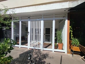 A covered outdoor area with a sliding glass door, potted plants, and a bench.