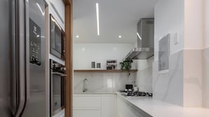 A modern kitchen with white cabinetry, stainless steel appliances, and a marble backsplash. - 5 Minutos Da Praia De Ipanema | J303 (Rio de Janeiro)