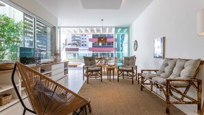 Una sala de estar moderna con un ventanal grande, muebles de mimbre, un sofá y una zona de comedor con sillas y una mesa.