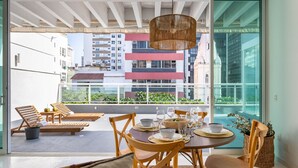 Un balcón con mesa para cuatro, sillas de madera y una lámpara colgante.