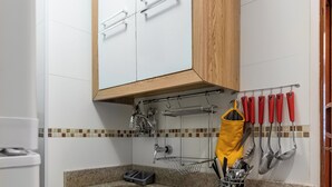 A compact kitchen with a built-in oven, a sink, and a wooden cabinet above the countertop. - Estudio Moderno Do Lado De Arpoador | Jc1012 Z2 (Rio de Janeiro)
