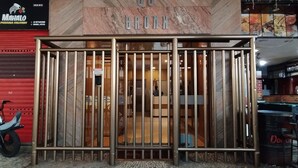 A building entrance with a metal gate, a tiled floor, and a sign above the gate. - Estúdio Em Copacabana | Ideal P/ Famílias|Jc509 (Rio de Janeiro)