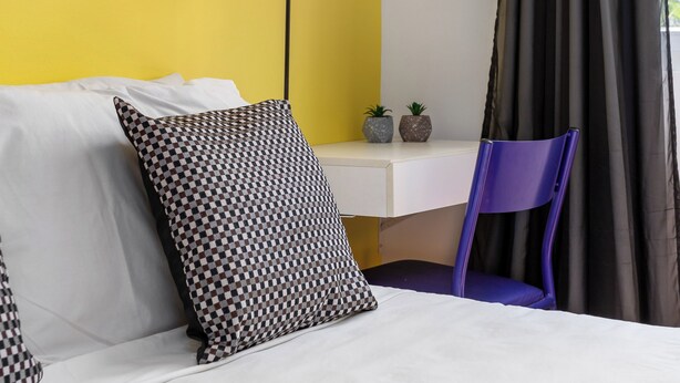 A hotel room with a bed, a desk, a lamp, a chair, and a window with curtains. - Estúdio Em Copacabana | Ideal P/ Famílias|Jc509 (Rio de Janeiro)