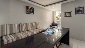 Een moderne woonkamer met een gestreept sofa, een eettafel met twee wijnglazen, en kunstwerken aan de wanden.