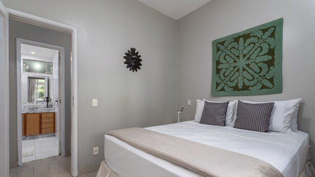 Een slaapkamer met een bed, een groot decoratief wandobject en uitzicht op de badkamer.