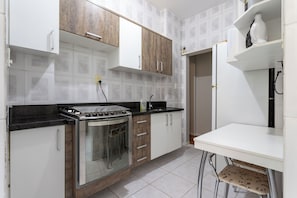 A kitchen with a stove, oven, and white cabinets. - 3 Minutos Da Praia De Ipanema | Pm203 (Rio de Janeiro)