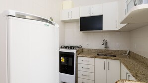 A compact kitchen with white cabinets, a built-in stove, and a microwave above the countertop. - 3 Minutos Da Praia De Ipanema | Pm402 (Rio de Janeiro)