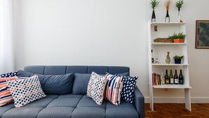 A modern living room with a grey sofa, patterned cushions, and a white shelving unit with books, decorative items, and wine bottles. - 3 Minutos Da Praia De Ipanema | Pm402 (Rio de Janeiro)