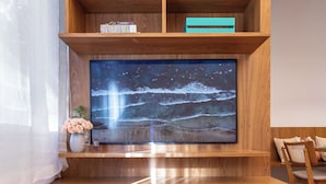 Un salon moderne avec un meuble TV en bois, un téléviseur à écran plat et un parquet à motifs en chevrons.