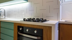 Une cuisine moderne avec des meubles en bois, un four encastré et une cuisinière à gaz.