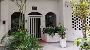 Un patio con plantas en macetas, una entrada con portón y un edificio con fachada de azulejos.
