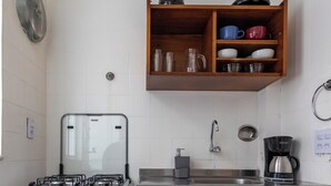 Una cocina compacta con estufa a gas, horno y cafetera.
