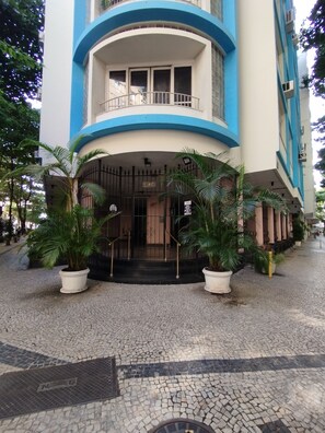 A building with a curved entrance, potted plants, and a cobblestone pathway. - Moderno Em Ipanema | Ótimo Para Famílias | Re406 Z2 (Rio de Janeiro)