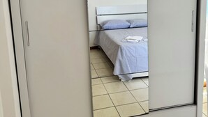 A room with a large wardrobe, a bed with striped bedding, and a tiled floor. - Refúgio Em Salvador Com Vista Para O Mar (Salvador)
