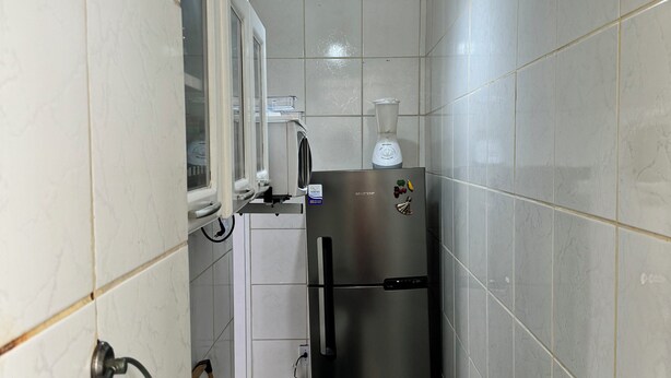 A compact kitchen with a gas stove, a stainless steel refrigerator, and a window above the sink. - Refúgio Em Salvador Com Vista Para O Mar (Salvador)