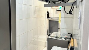 A kitchen with white tiled walls, a gas stove, and a microwave. - Refúgio Em Salvador Com Vista Para O Mar (Salvador)