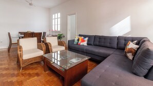 A living room with a sofa, two armchairs, a glass coffee table, and a dining area with a table and chairs. - Sofisticado A Poucos Passos Da Lagoa | Sb301 (Rio de Janeiro)