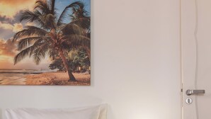 A bedroom with a bed, a nightstand with a lamp, a door, and a wall with a painting. - Sofisticado A Poucos Passos Da Lagoa | Sb301 (Rio de Janeiro)