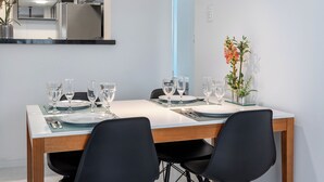 Zona pranzo moderna con tavolo rettangolare apparecchiato per quattro persone, sedie nere e lampade a sospensione.