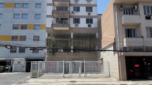 Un edificio a più piani con balconi, un ingresso sorvegliato e un cartello visibile per un'attività commerciale.