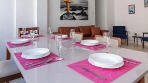 Un comedor moderno con una mesa blanca dispuesta para seis comensales, individuales rosa y lámparas colgantes rojas.