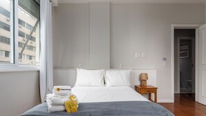 A hotel room with a large bed, a bedside table with a lamp, and a view of the city through the window. - Para Famílias 3Min Da Praia De Copacabana | Sl501 (Rio de Janeiro)
