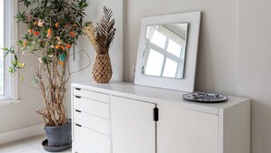 A white cabinet with a mirror and a decorative vase, a potted plant, and an air conditioning unit on the wall. - Para Famílias 3Min Da Praia De Copacabana | Sl501 (Rio de Janeiro)