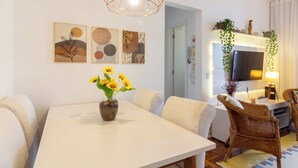 A modern living room with a white dining table, wicker chairs, a TV, and artwork on the wall. - 4 Minutos Do Arcos Da Lapa | Sr1502 (Rio de Janeiro)