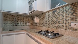 A kitchen with a gas stove, white cabinets, a microwave, and a tiled backsplash. - 3 Minutos Da Praia De Copacabana | Stc303 (Rio de Janeiro)