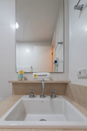 A bathroom with a white sink, three faucets, a mirror, and a towel rack with a 'PINEAPPLES' towel. - 3 Minutos Da Praia De Copacabana | Stc303 (Rio de Janeiro)