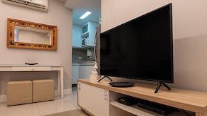 A modern living room with a flat-screen TV on a wooden stand, a small desk with a chair, and a sofa. - 3 Minutos Da Praia De Copacabana | Stc303 (Rio de Janeiro)