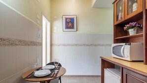 A compact kitchen with a dining table set for two, a microwave, and a refrigerator. - 5 Minutos Da Praia De Copacabana | Stc905 (Rio de Janeiro)