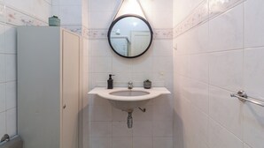 A bathroom with a white sink, a round mirror, and a toilet. - 5 Minutos Da Praia De Copacabana | Stc905 (Rio de Janeiro)