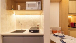 A compact kitchen with a microwave, sink, and a small dining table set for two. - Aconchegante A Poucos Minutos Da Lagoa | Vlp412 (Rio de Janeiro)